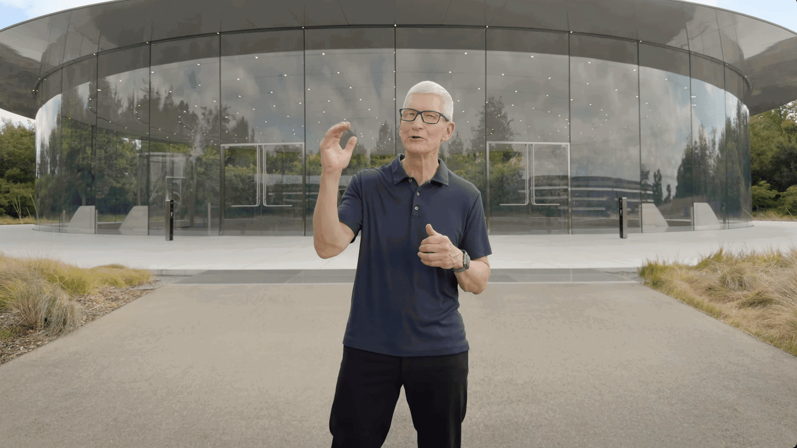 Apple Chef Tim Cook spricht vor modernem Glasgebäude.