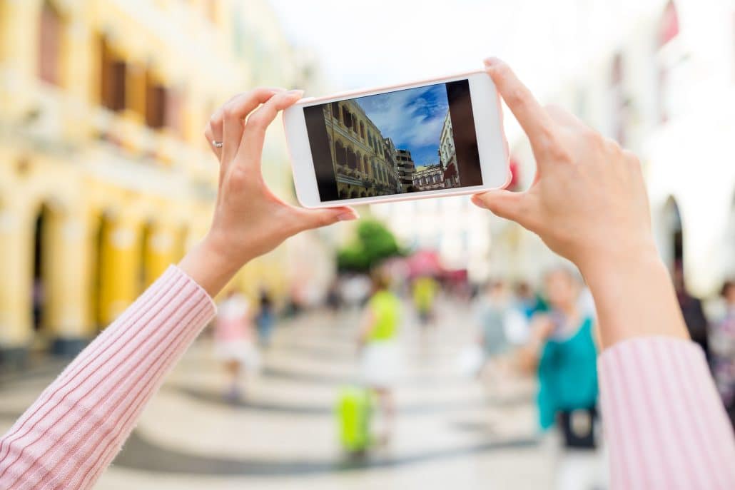Person fotografiert Gebäude mit Smartphone in Stadt.