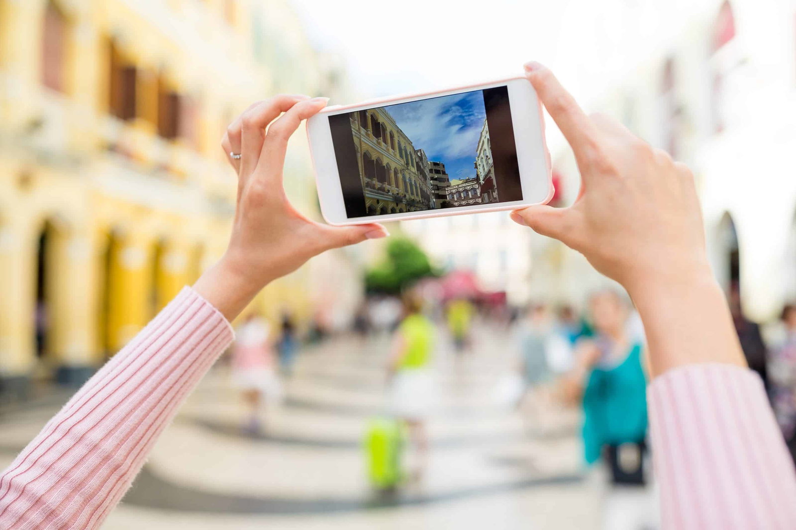 Person fotografiert Gebäude mit Smartphone in Stadt.