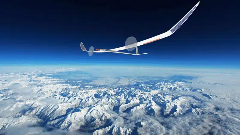 Solarflugzeug über schneebedeckten Bergen und Wolken