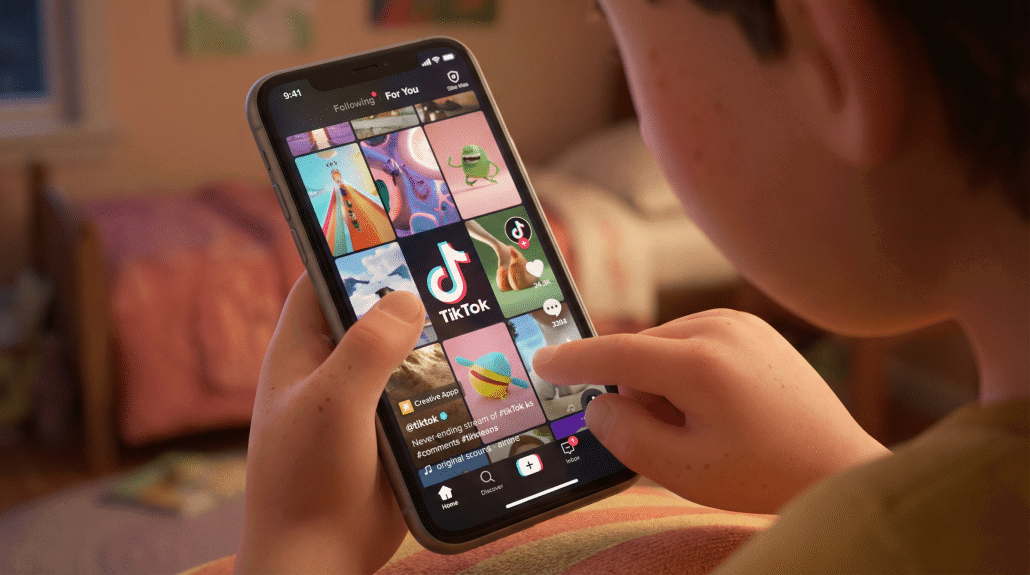 Junge scrollt durch TikTok auf dem Handy