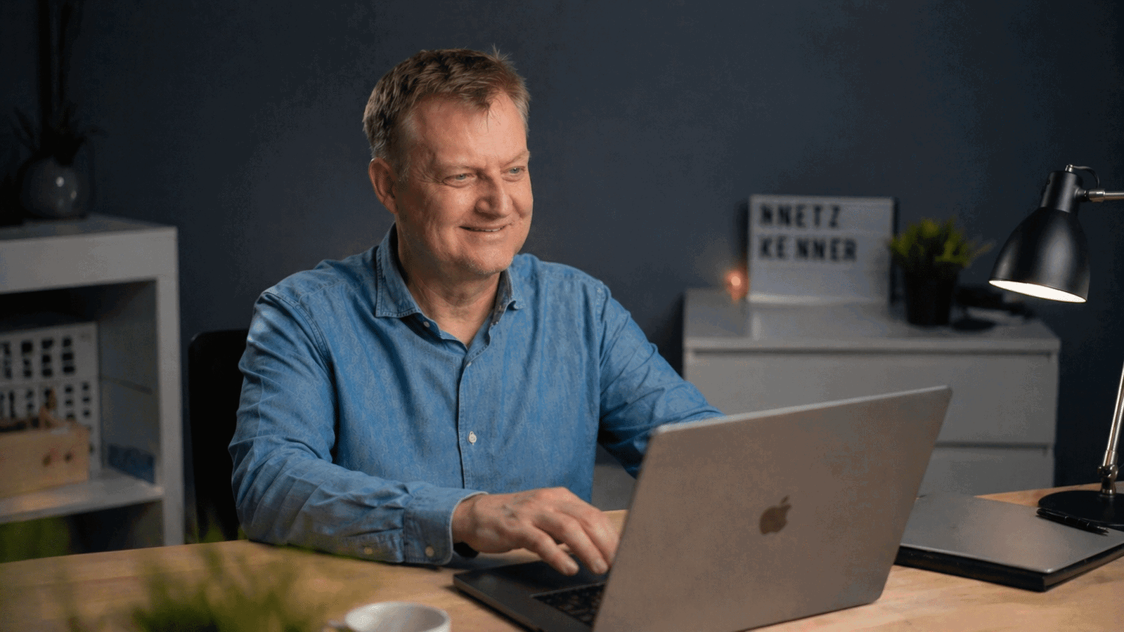 Mann arbeitet lächelnd am Laptop im Homeoffice