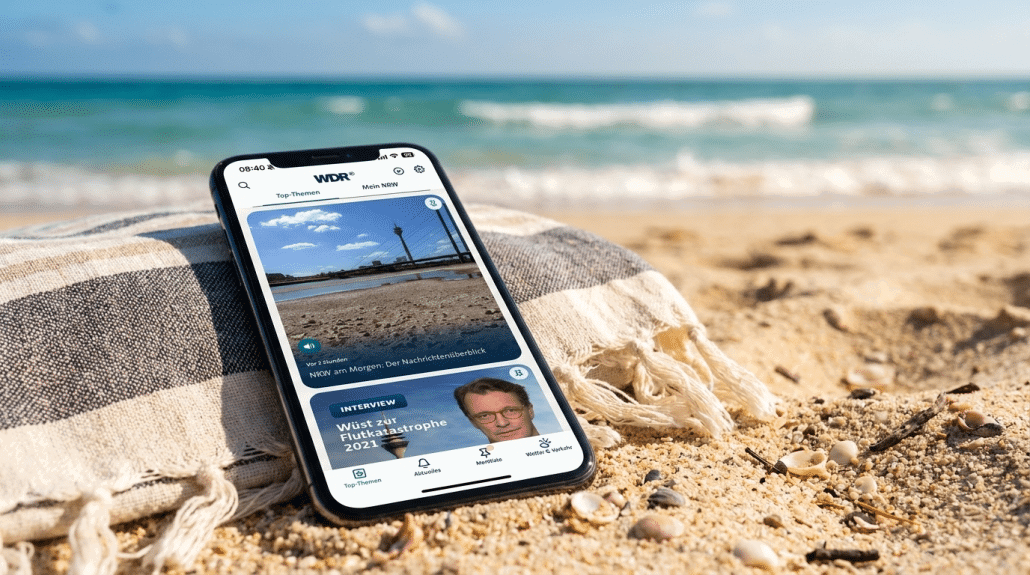 Smartphone mit Nachrichten-App am Strand im Sand